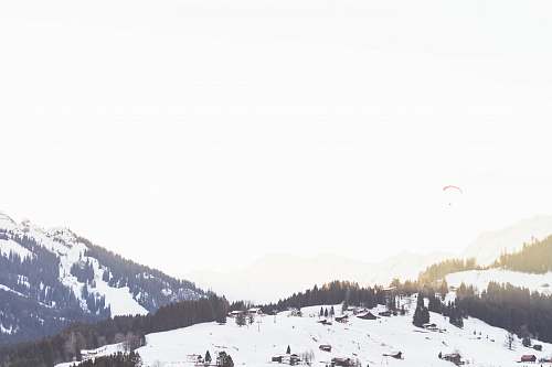 nature aerial photography of houses on snowy hill alps