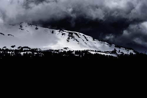 sky grayscale photo of mountain during winter outdoors