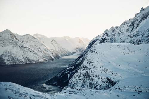 snow landscape photography of snow-coated mountains near body of water during daytime nature