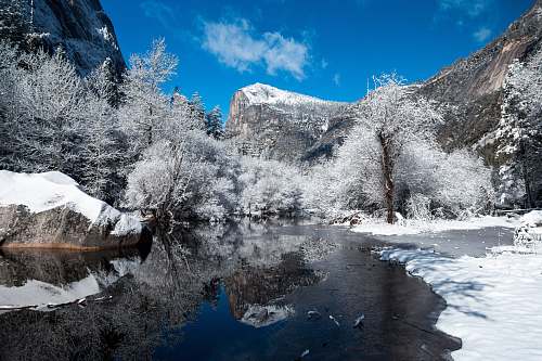 snow snow capped mountain near river at daytime blue