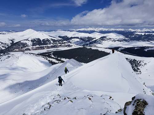 nature two people walking on snowy mountain during daytime outdoors