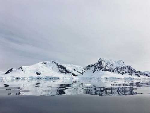 mountain body of water near snow capped mountain snow