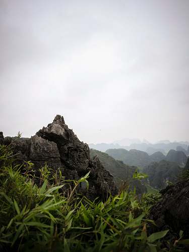 outdoors grass near rock under cloudy sky at daytime slope