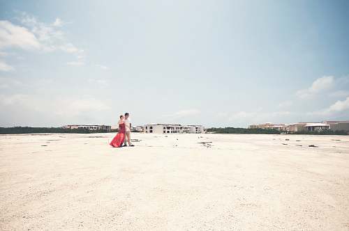beach man and woman standing on open field during daytime coast