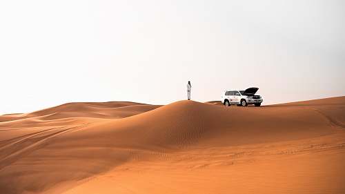 outdoors person standing beside silver SUV during daytime soil