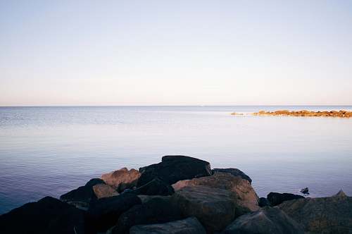 shoreline rocks beside body of water water