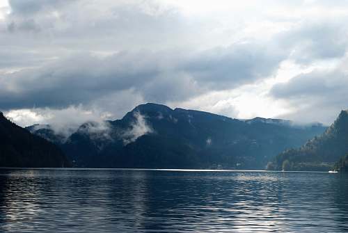 outdoors silhouette photo of mountains beside sea water
