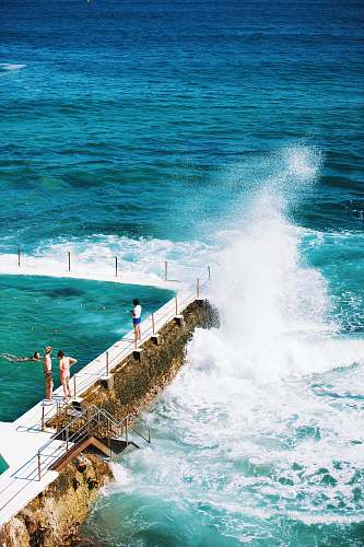 coast people standing beside pool next to the sea sea