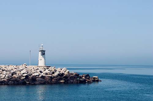 sea photograph of white lighthouse on rocks water