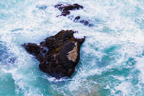 waves scenery of a rock on a body of water water