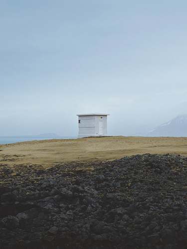 sea white wooden shed on top of hill iceland