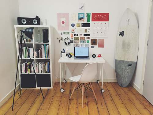 surfboard white surfboard beside white wall white wooden cube bookshelf inside the room workspace