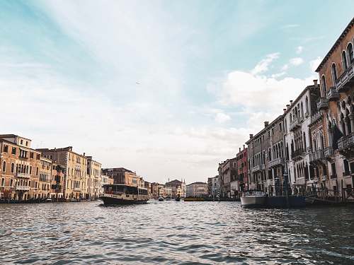 water boats on river alongside buildings during daytime boat
