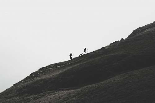 black-and-white silhouette of person walking on mountain slope