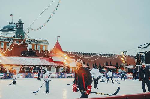 person people playing ice hockey near brown concrete building during daytime human