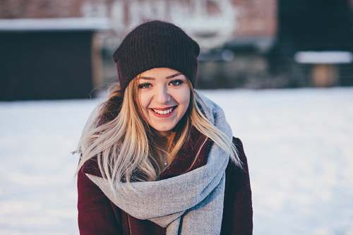 woman smiling woman wearing brown scarf and maroon coat on snow field girl