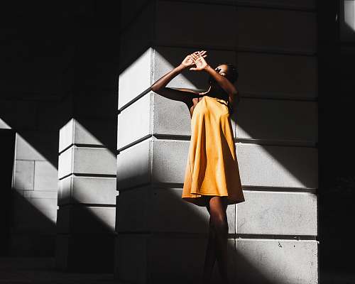human woman in orange dress and standing near white post woman