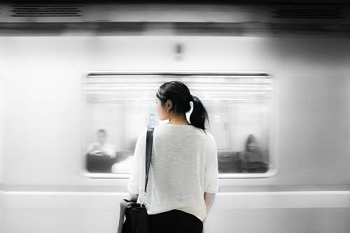 woman woman in white elbow-sleeved shirt standing near white train in subway human