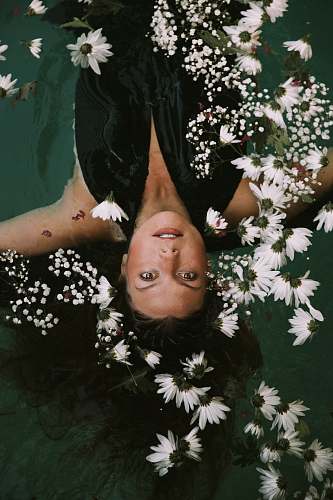 person woman swimming covered by white daisies woman
