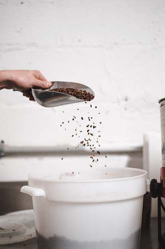 human brown grain scooped from white plastic container bowl