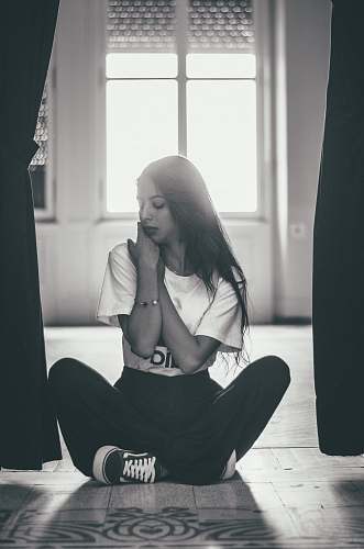human gray scale photography of woman sitting near between curtain people