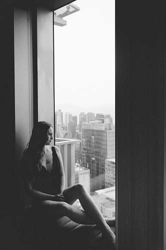 human grayscale photo of woman sitting on the mirror black-and-white