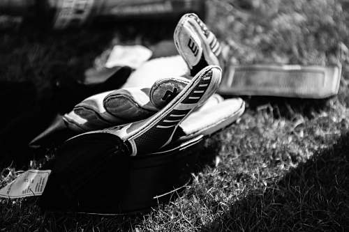 human greyscale photo pair of gloves on grass field black-and-white