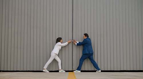 human man and woman standing beside gray wall people