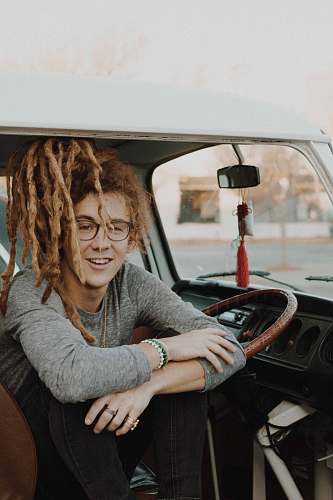 human man sitting inside car resting his hand on wheel during daytime people
