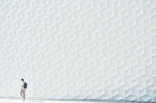 grey man walking beside white wall pillow