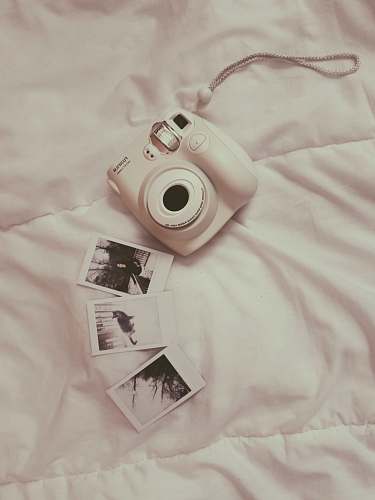 human white Fujifilm instant camera on white comforter people