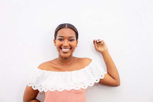 human woman in white and pink off-shoulder top standing beside wall female