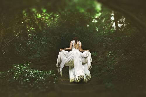 people woman in white dress walking on pathway surrounded by trees wedding