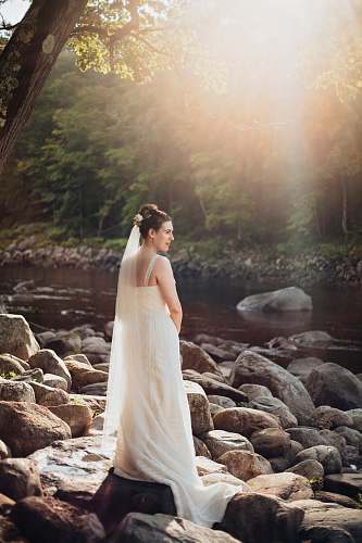 nature woman standing on gray rock near lake during sunset rock