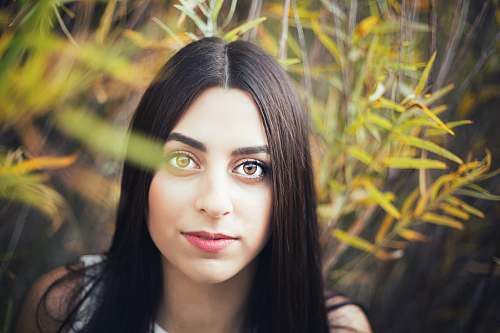 human woman with long black hair in front of green grass face
