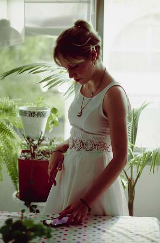 human women's white sleeveless dress using smartphone on table people