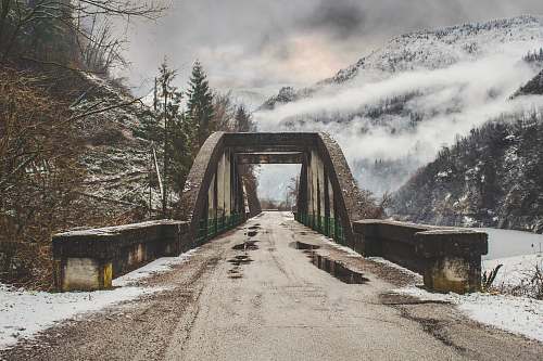 nature gray concrete arch bride beside leafless tree near mountain range bridge