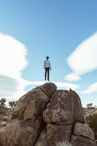 blue man jump on brown boulder joshua tree