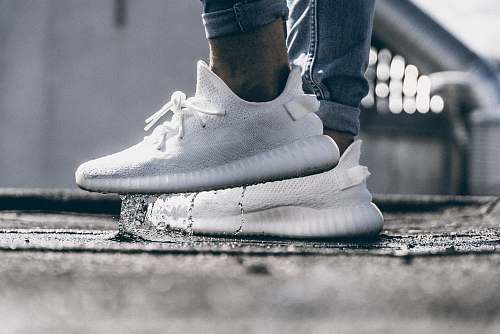 white person wearing pair of cream white Adidas Yeezy Boost 350 shoes adidas