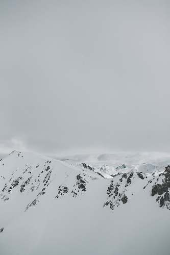 grey aerial photography of snow covered mountain peak winter