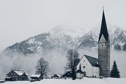 winter bird's-eye view photography of houses and cathedral near snow mountain grey