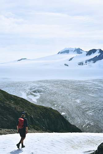 person man walking on snow facing mountain mountain