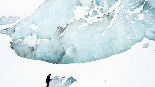 glacier person standing on snow field near mountain ice