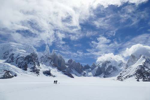 mountain two persons standing near mountain during winter season glacier