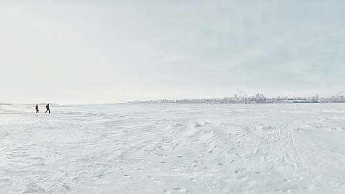 grey two persons walking on sand under clear sky winter
