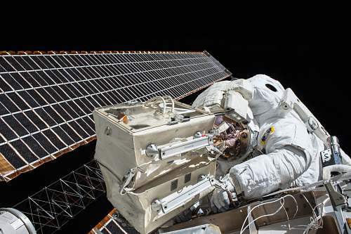 nasa closeup photo of astronaut repairing satellite astronaut