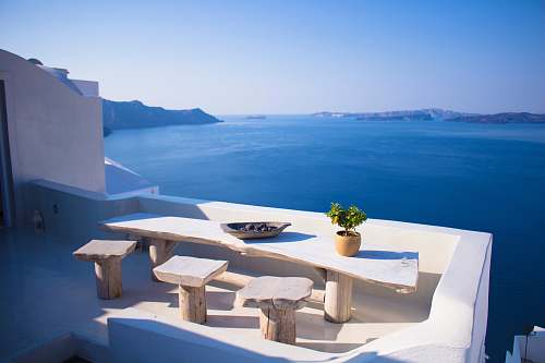 greece bench and dining table near body of water under calm sky hotel