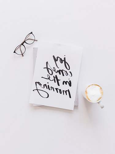 handwriting brown framed eyeglasses,latte, and joy comes in the morning note on white surface calligraphy