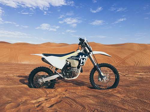 motorcycle black and white dirt bike on sand blue