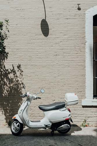 grey white and black motor scooter beside white wall scooter